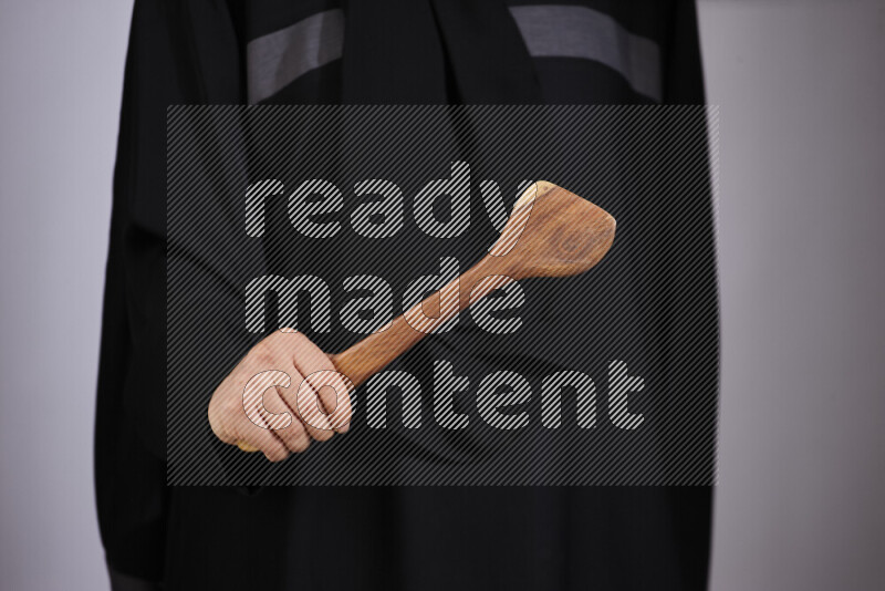 امرأة ترتدي عباءة سوداء تحمل أدوات خشبية مختلفة في أوضاع متعددة