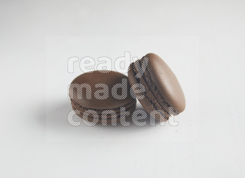 45º Shot of two Brown Dark Chocolate macarons on white background
