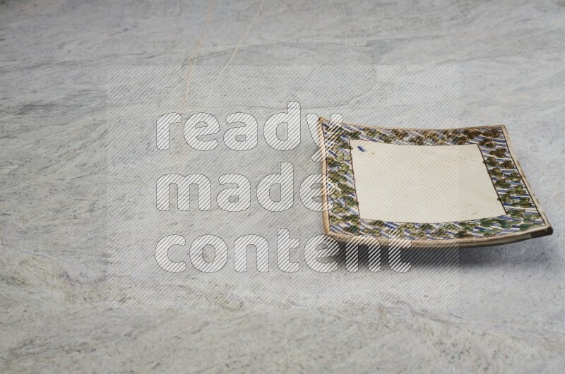 A decorative pottery plate on grey marble background