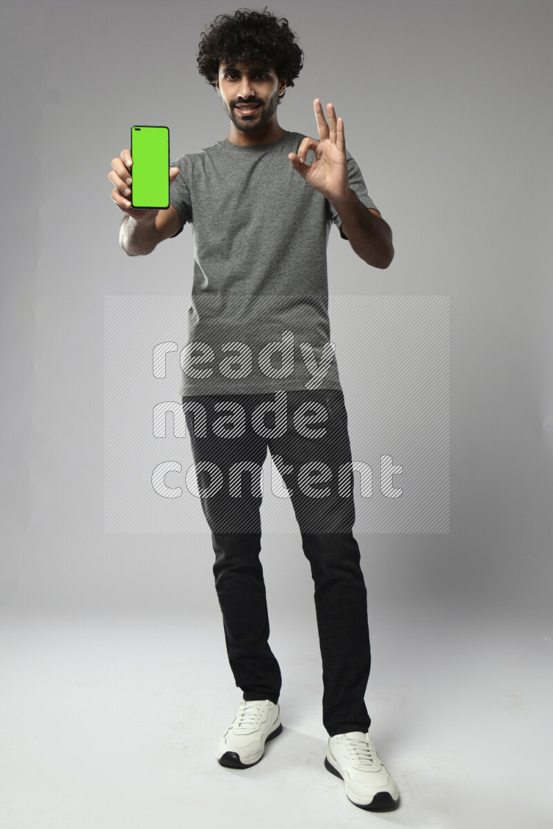 A man wearing casual standing and showing a phone screen on white background