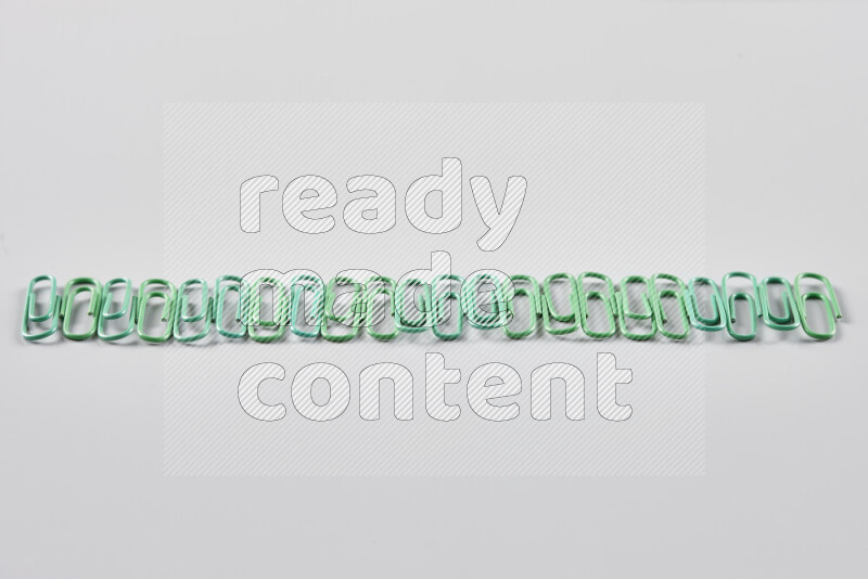 Green paper clips isolated on a grey background