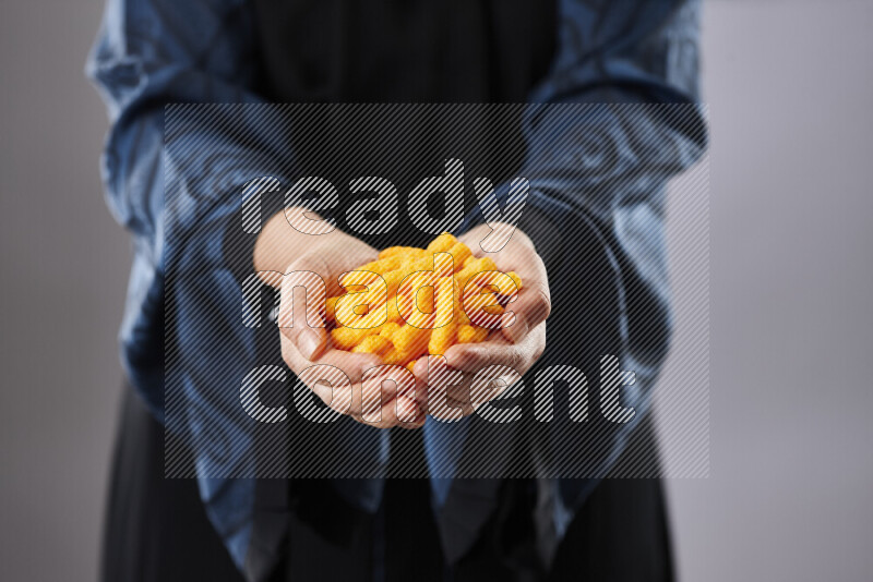 Woman in abaya holding different kinds of snacks in different positions