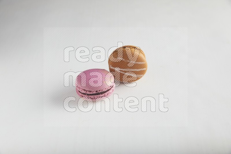 45º Shot of of two assorted Brown Irish Cream, and Purple Strawberry macarons on white background