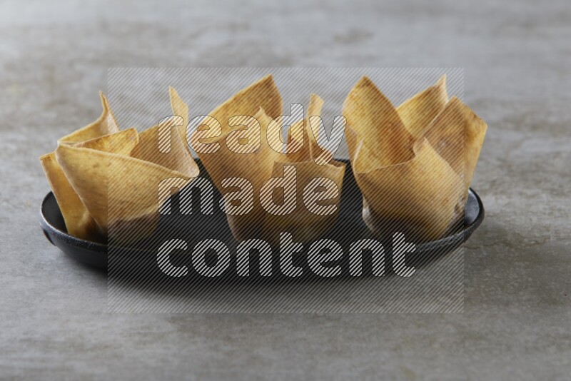 wonton cups on oval black ceramic plate on grey textured counter top