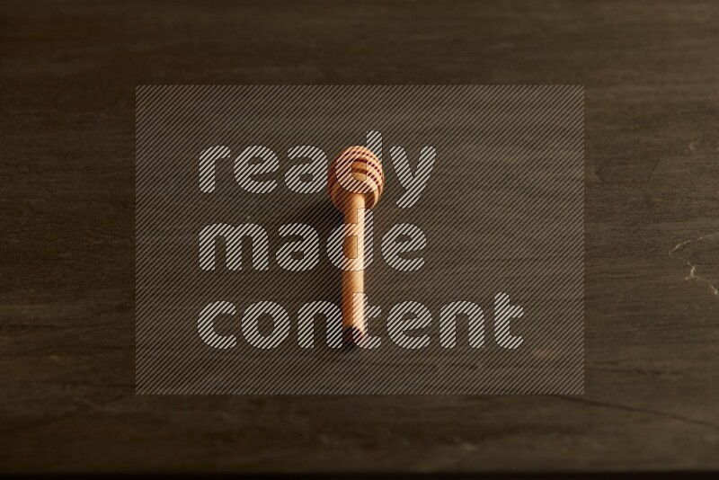 Wooden honey dipper on black slate background