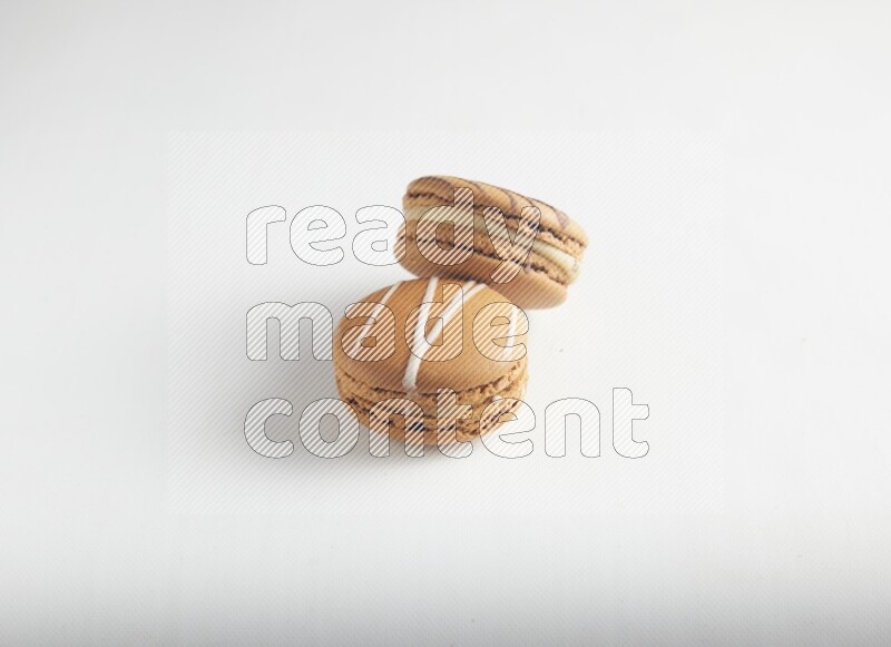 45º Shot of of two assorted Brown Irish Cream, and light brown  Almond Cream macarons on white background