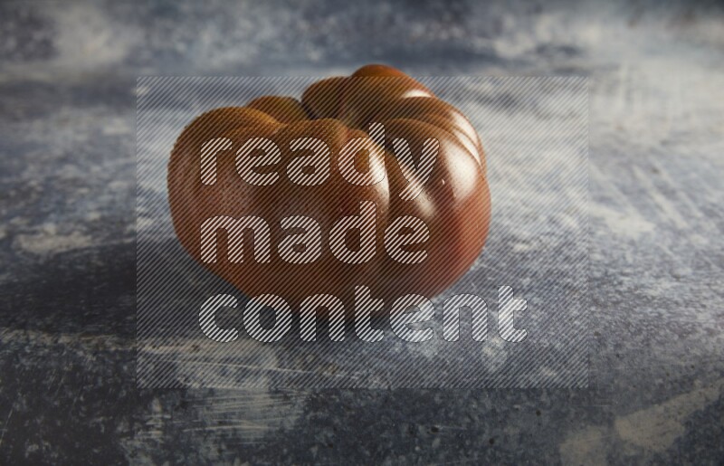 45 degree single heirloom tomato on a textured rustic blue background