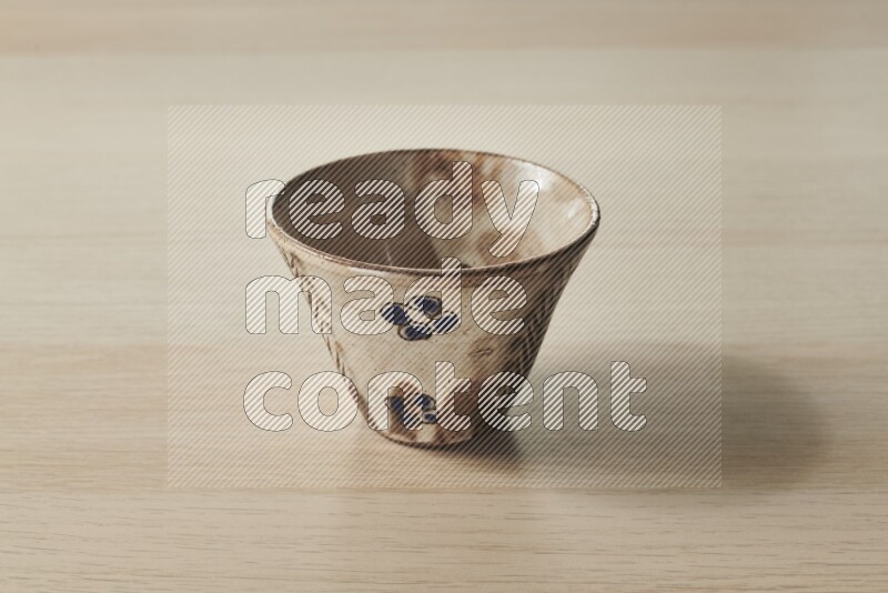 A decorative pottery bowl on light wooden background