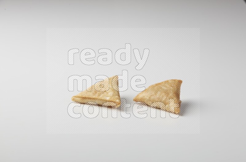 Two fried sambosas on a white background