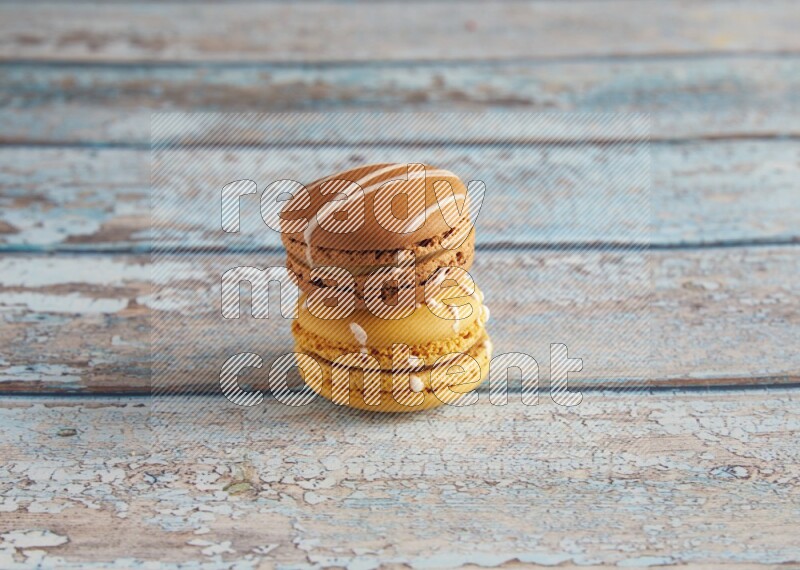 45º Shot of of two assorted Brown Irish Cream, and Yellow Piña Colada macarons on light blue background