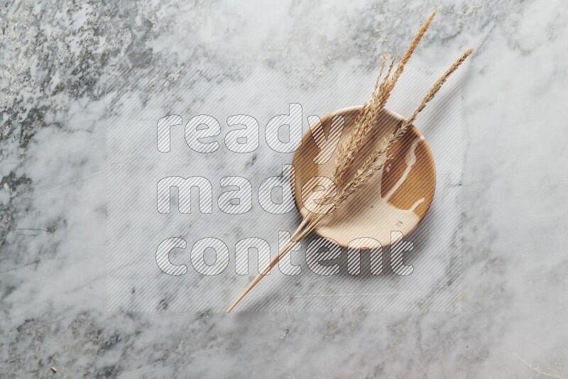 Wheat stalks on multicolored pottery plate on grey marble background