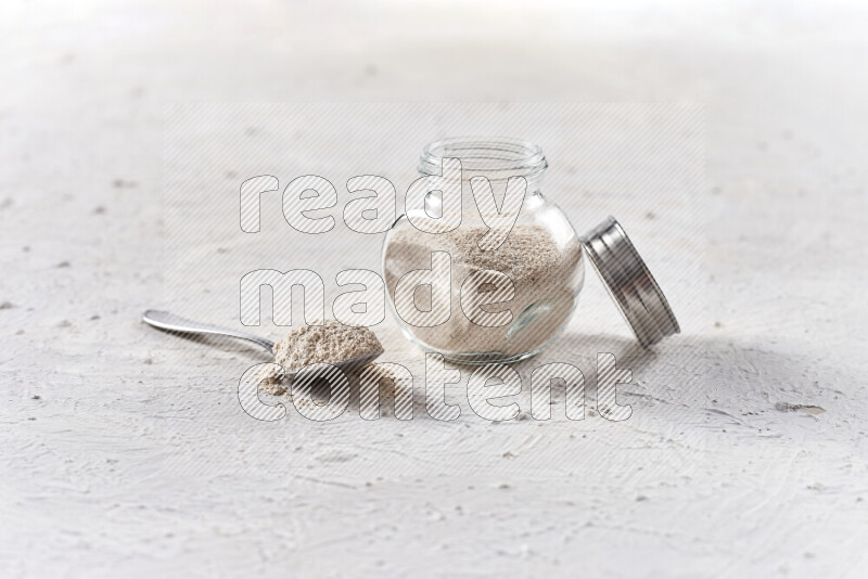 A glass jar full of onion powder on white background