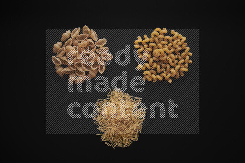 Different pasta types in bunches on black background