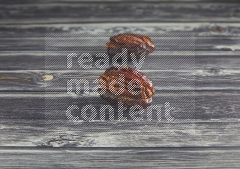 two pecan stuffed madjoul date on a wooden grey background