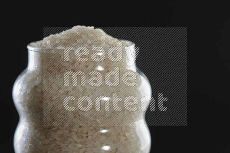 White rice in a glass jar on black background