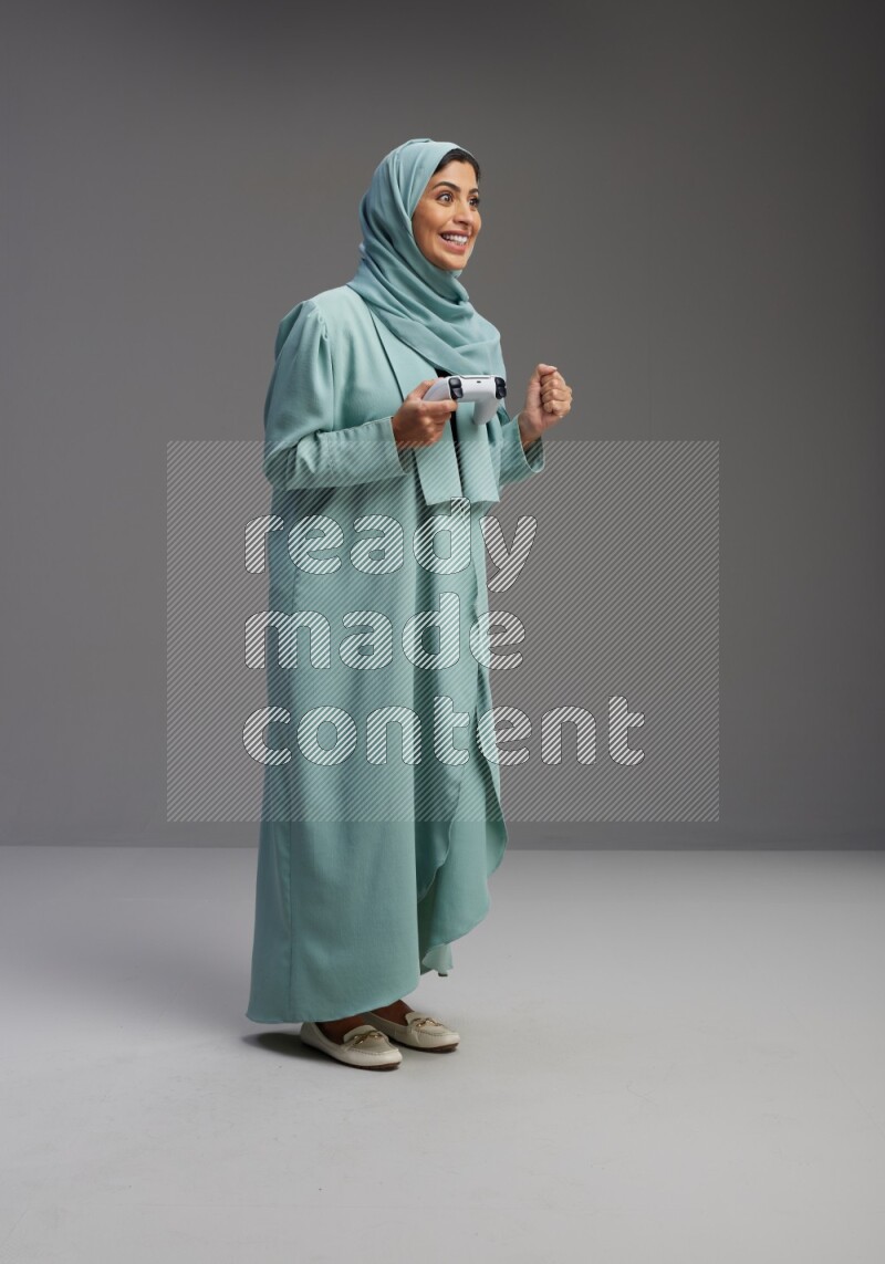 Saudi Woman wearing Abaya standing Playing Games on Gray background
