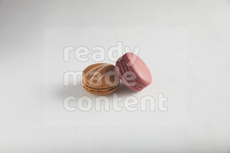 45º Shot of of two assorted Brown Irish Cream, and Red Velvet macarons on white background