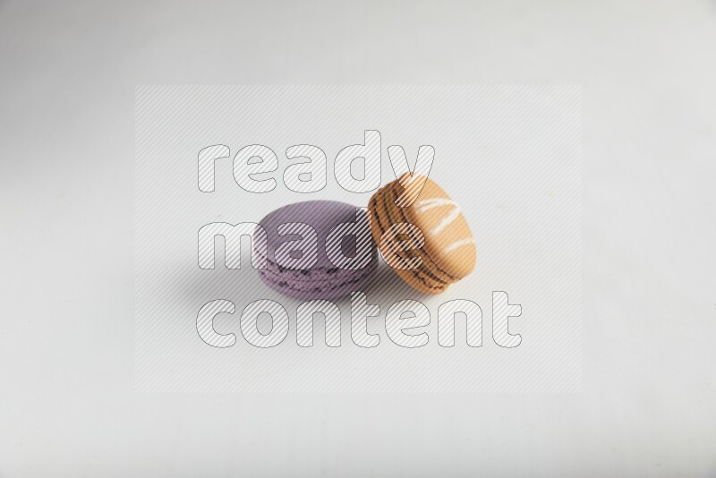 45º Shot of of two assorted Brown Irish Cream, and Purple Blueberry macarons on white background