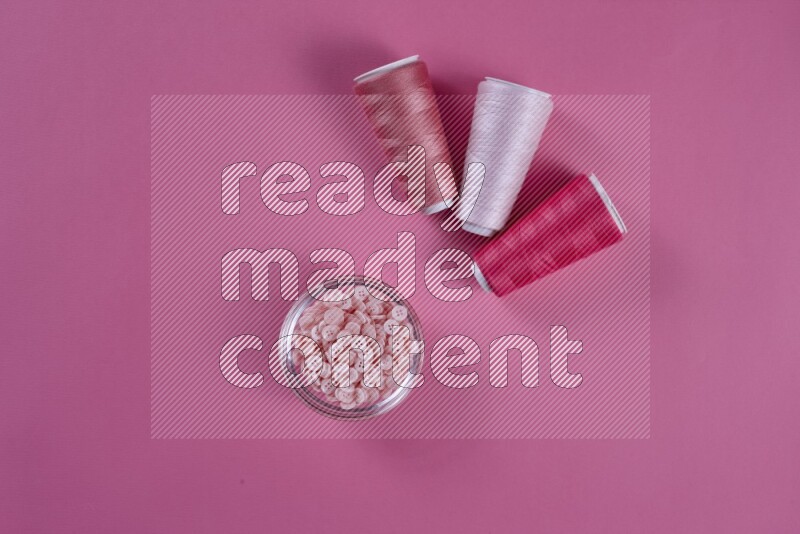 A pink collection of sewing and tailoring tools arranged on a pink background