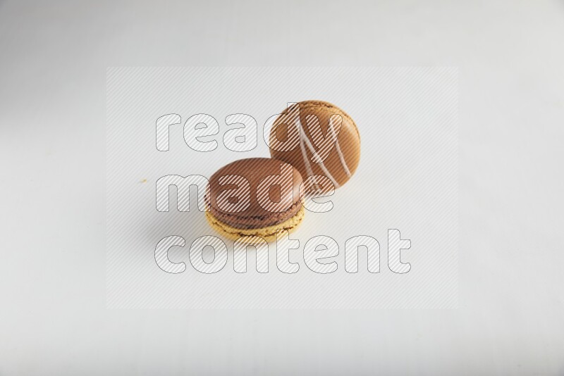 45º Shot of of two assorted Brown Irish Cream, and Yellow, and Brown Chai Latte macarons on white background