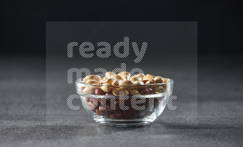 A glass bowl full of peeled peanuts on a black background in different angles