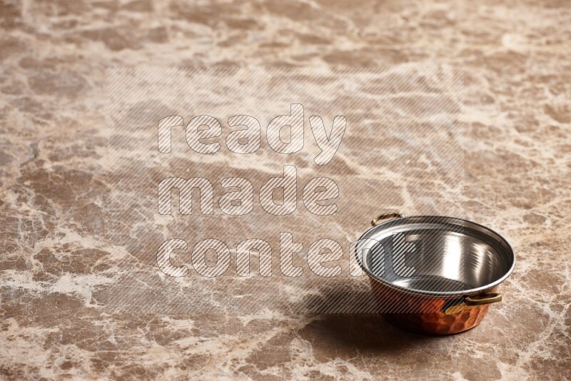 A small copper pot on beige marble background