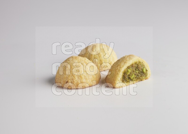Three Pieces of Maamoul filled with pistachio paste  one of them is cut direct on white background