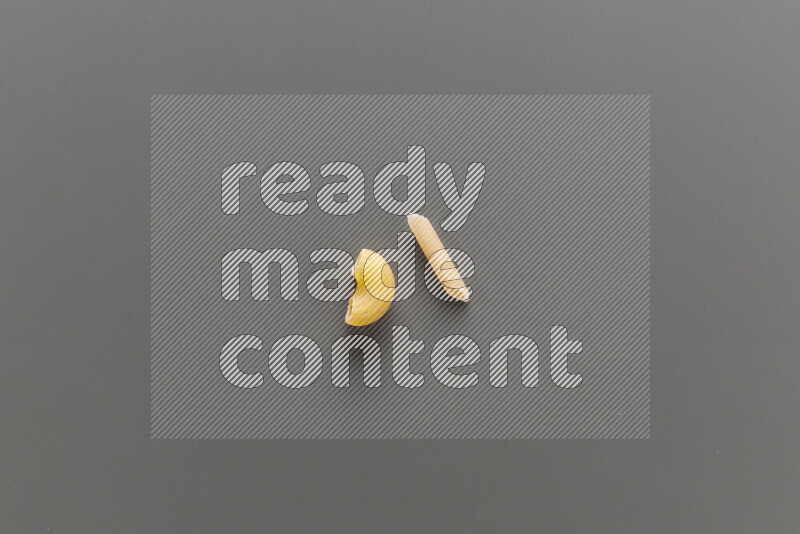 Elbow pasta with other types of pasta on grey background