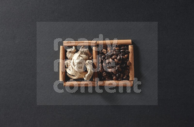 مربعان من أعواد القرفة ممتلئان بحبوب القهوة والزنجبيل المجفف علي خلفية سوداء