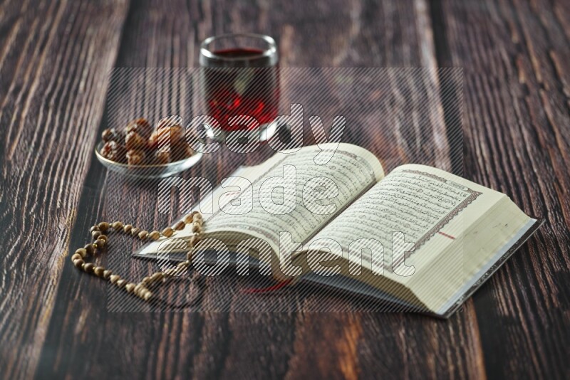 Quran with dates, prayer beads and different drinks all placed on wooden background