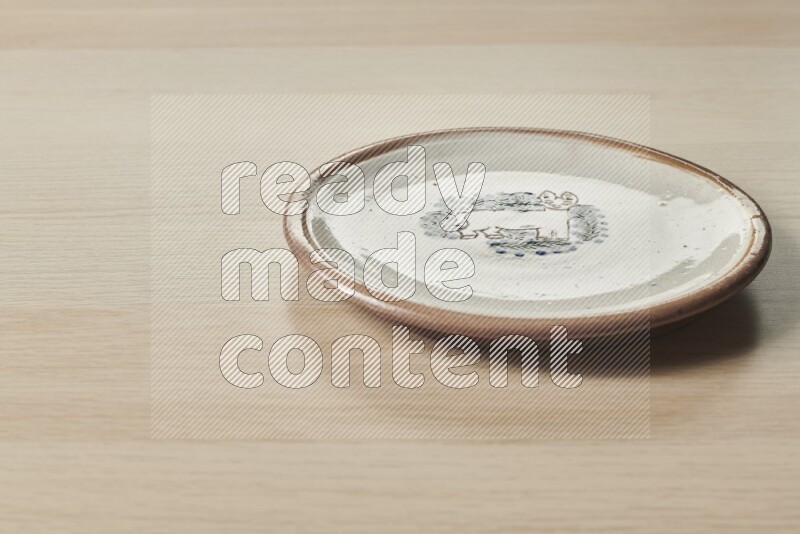 A decorative pottery plate on light wooden background