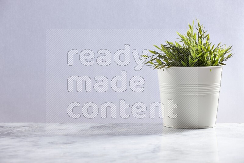 Green artificial plant in white pot on grey marble background