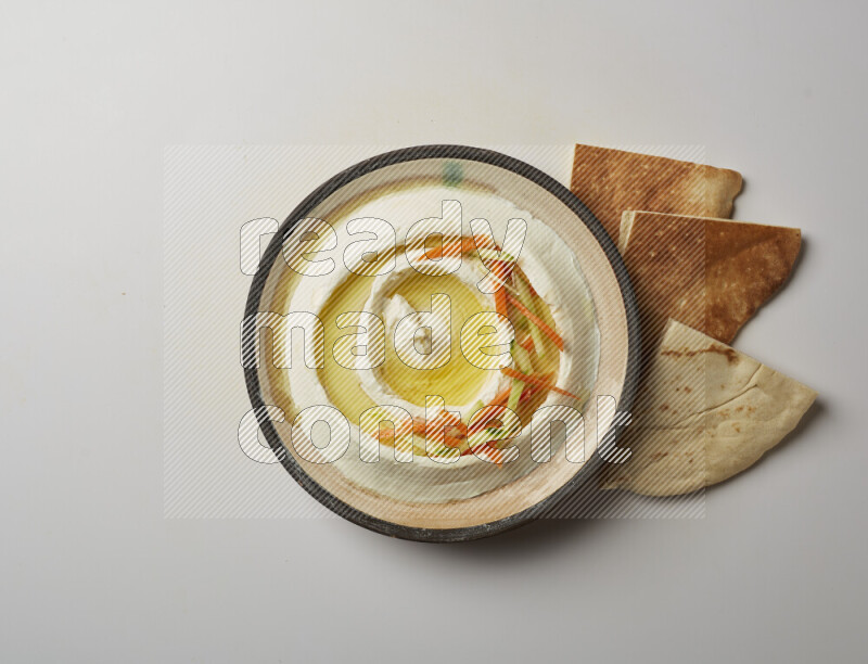 Lebnah garnished with sliced carrots &cucumber in a pottery plate on a white background