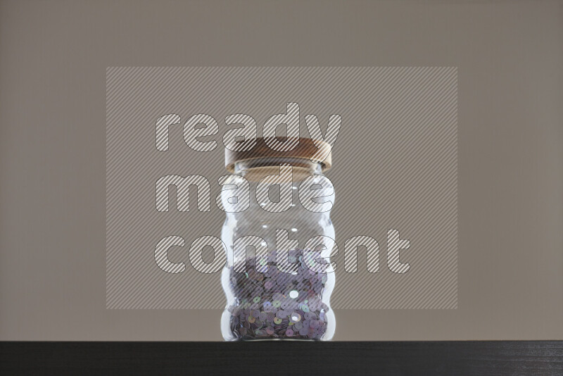 Sequins in a glass jar on black background