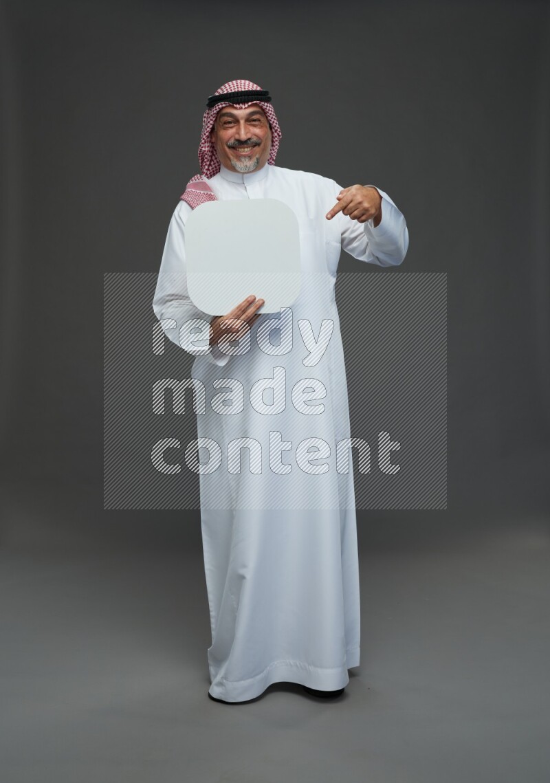 Saudi man with shomag Standing holding social media sing on gray background