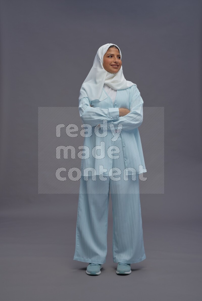 Saudi woman wearing hijab clothes standing with crossed arms on gray background