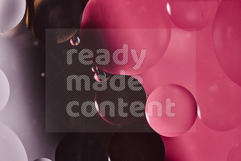 Close-ups of abstract oil bubbles on water surface in shades of black and pink