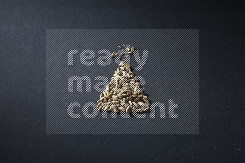 Cardamom in a triangle shape on black flooring