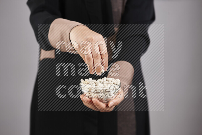 Woman in abaya holding different kinds of legumes in different positions