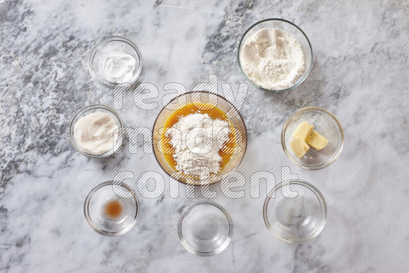 كوكيز خطوة بخطوة بمكوناتها، الدقيق، الزبدة، السكر البني، البيض، الفانيليا، السكر الأبيض، رقائق الشوكولاتة وصودا الخبز على خلفية رخام رمادي