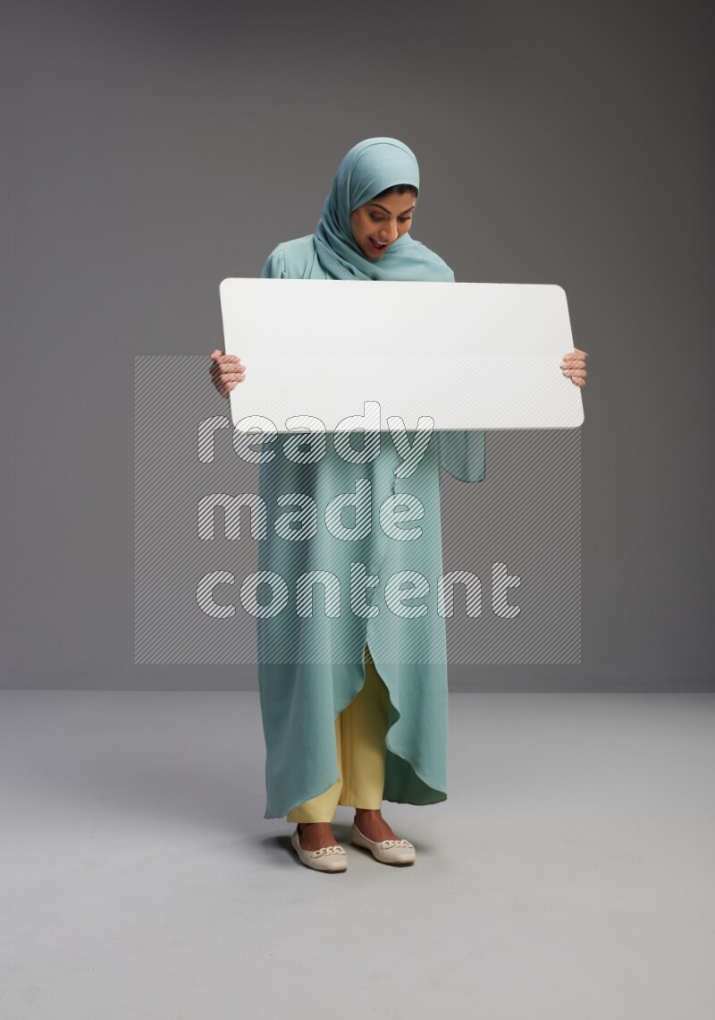 Saudi Woman wearing Abaya standing holding board on Gray background