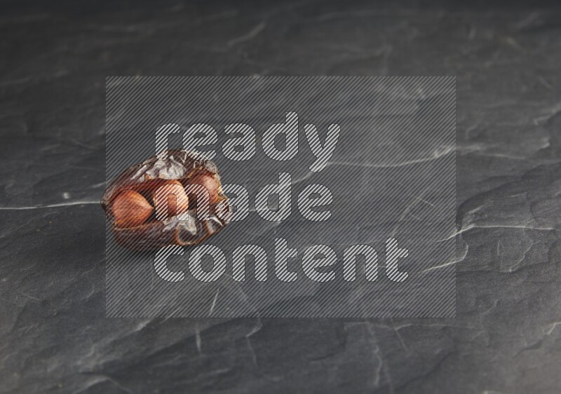 hazelnuts stuffed madjoul date on a black textured background