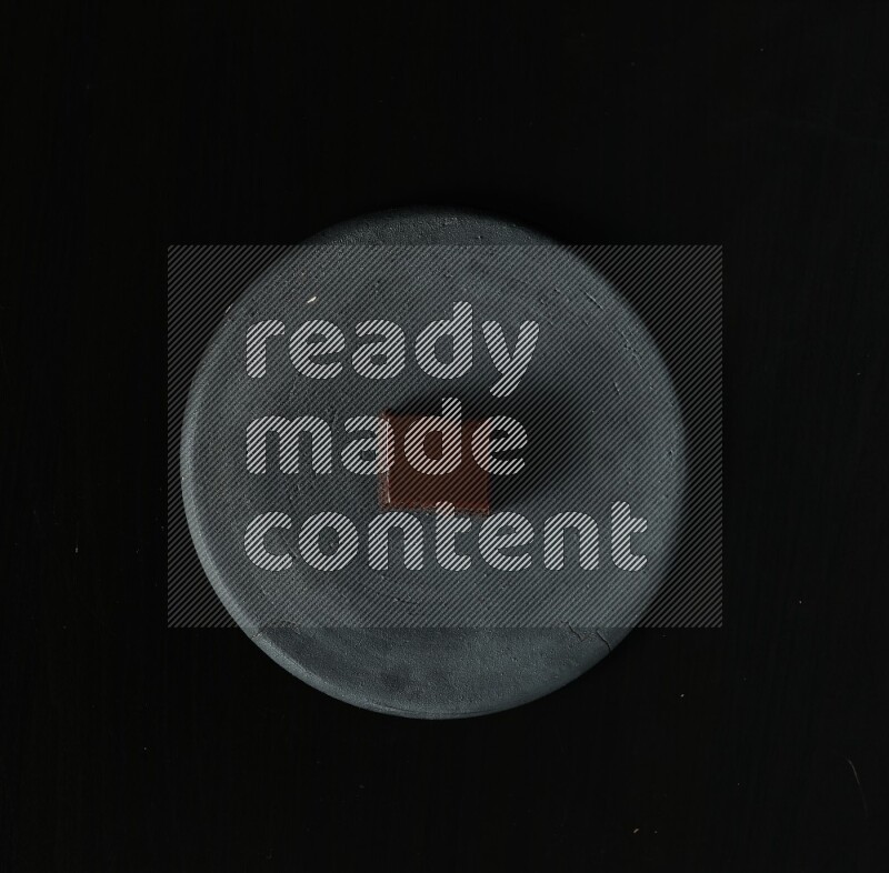 Assorted desserts in a black pottery plate on black background