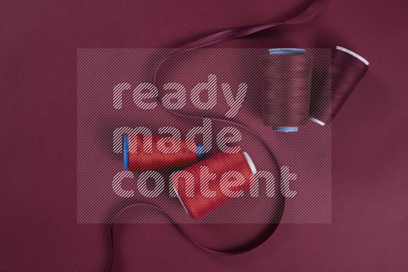 مجموعة من أدوات الخياطة والتفصيل حمراء اللون على خلفية حمراء