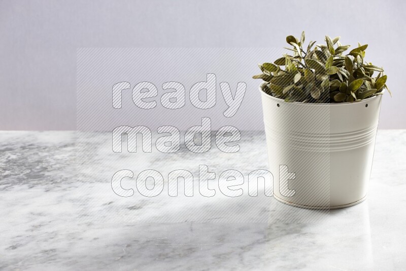 Green artificial plant in white pot on light grey marble background