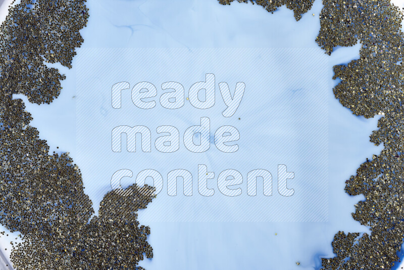 A close-up of sparkling gold glitter scattered on swirling blue background