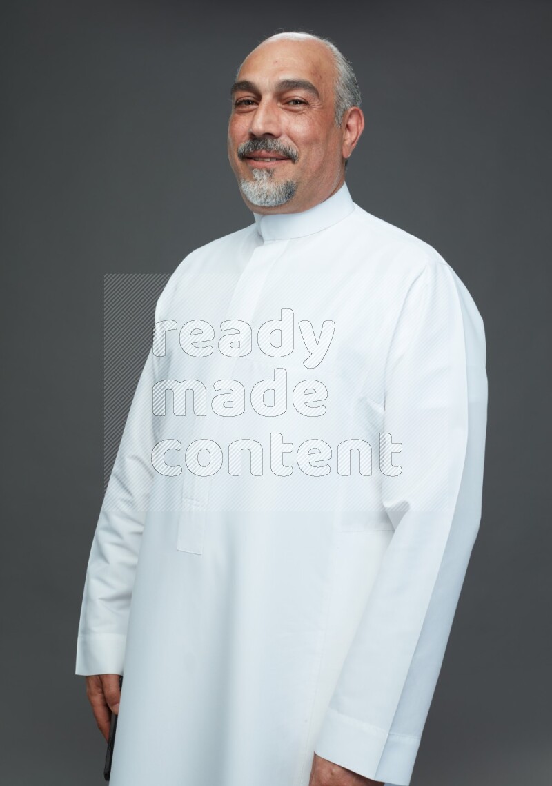 Saudi man without shomag Standing Interacting with the camera on gray background