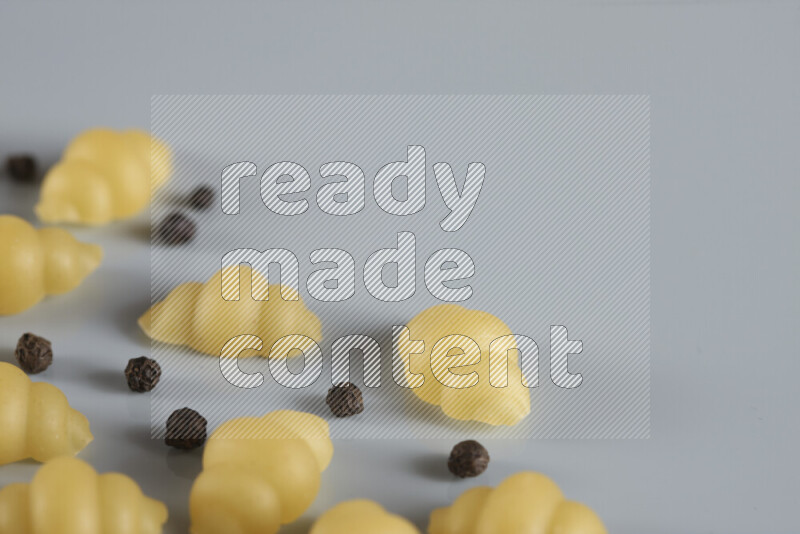 Raw pasta with different ingredients such as cherry tomatoes, garlic, onions, red chilis, black pepper, white pepper, bay laurel leaves, rosemary, cardamom and mushrooms on light blue background