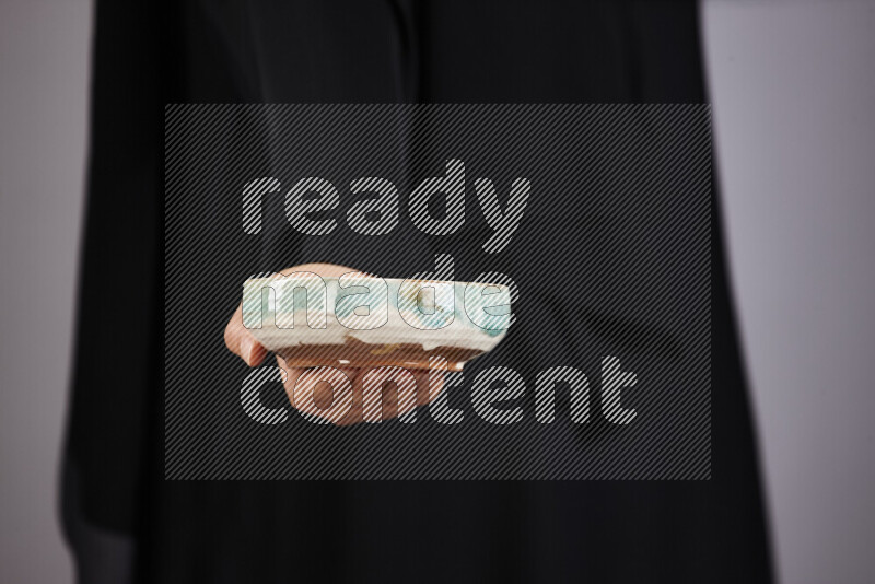 A woman in black abaya holding different pottery essentials in different positions