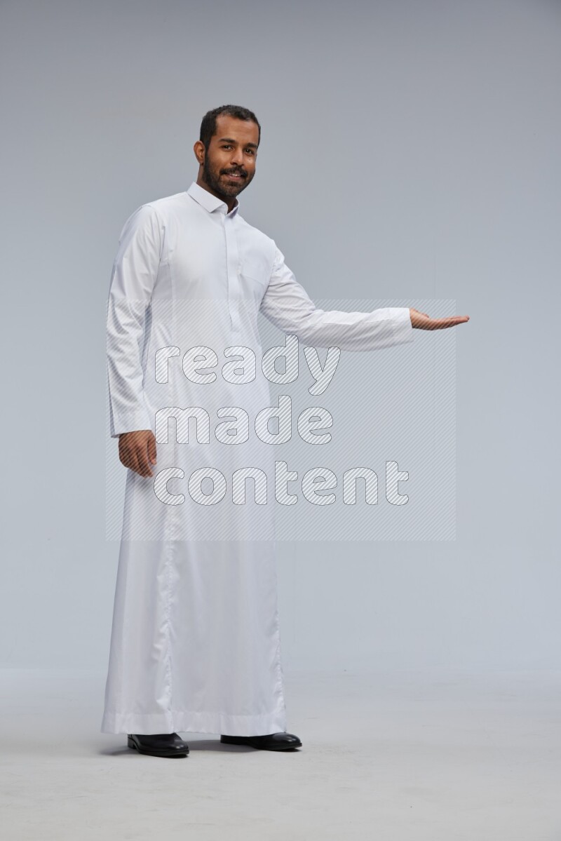 Saudi man Wearing Thob standing interacting with the camera on Gray background